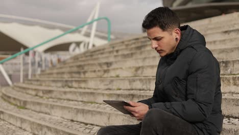 Concentrated-young-freelancer-working-with-tablet-outdoor